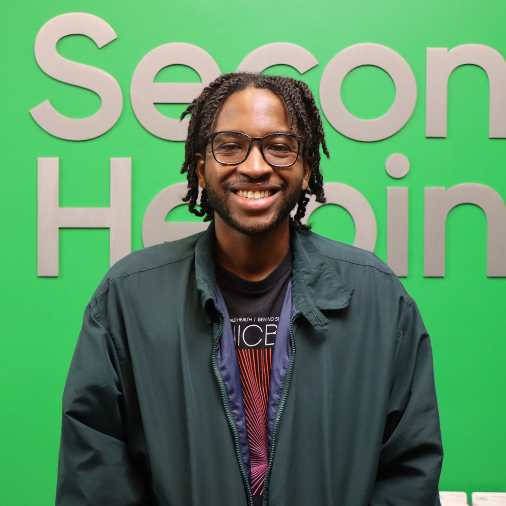 Keion smiling, with brown glasses wearing a green jacket