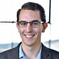 Logan Metzger A headshot of Logan wearing glasses and a suit