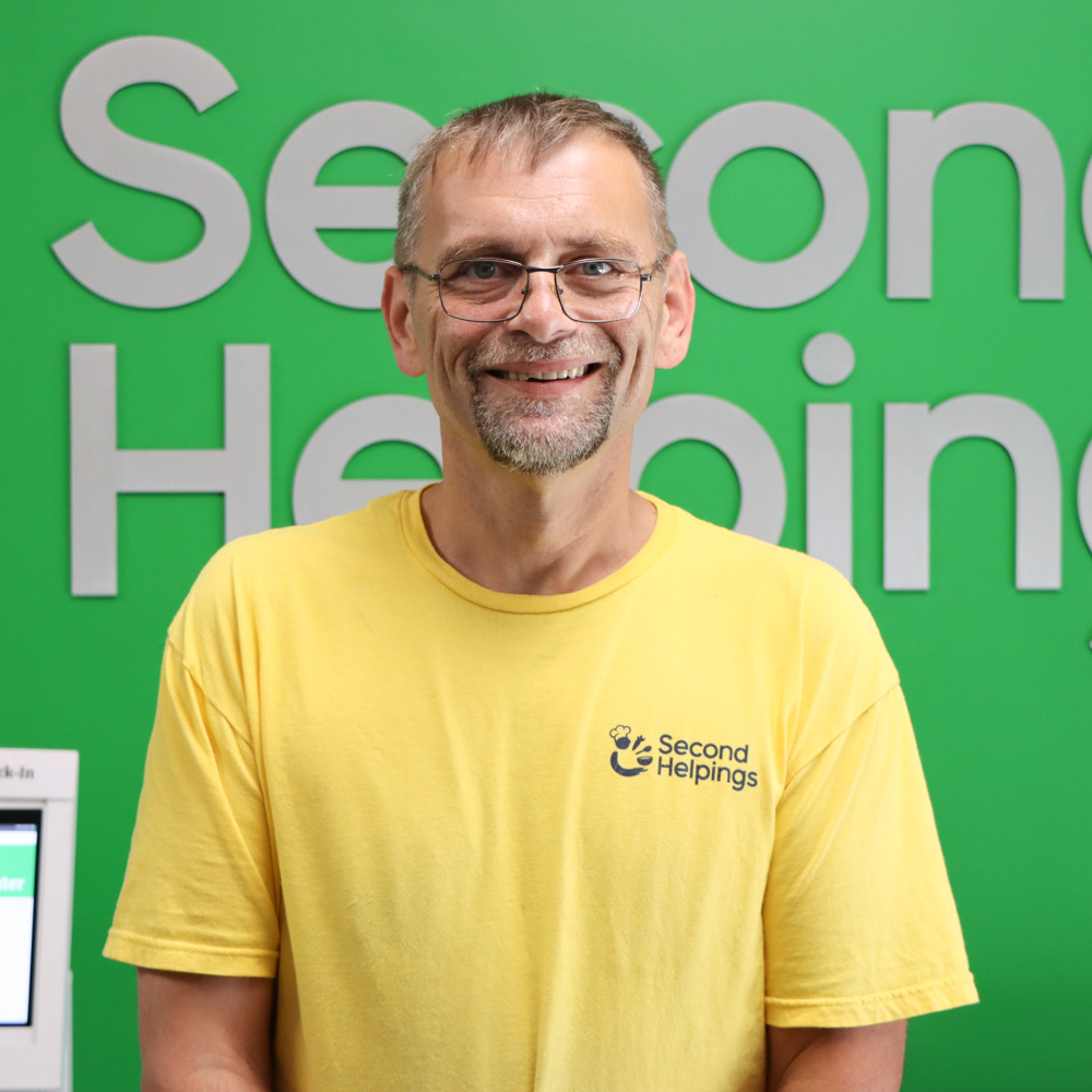 Kevin Murphy Kevin smiling, with glasses, wearing a yellow Second Helpings shirt
